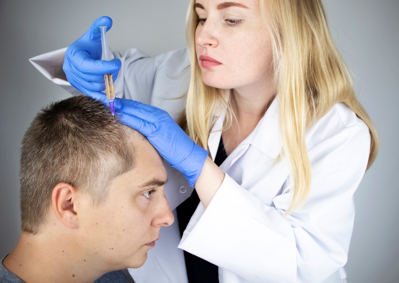 Pengobatan rambut rontok, seorang dokter menyuntikkan obat ke kepala seorang pria, seorang pasien