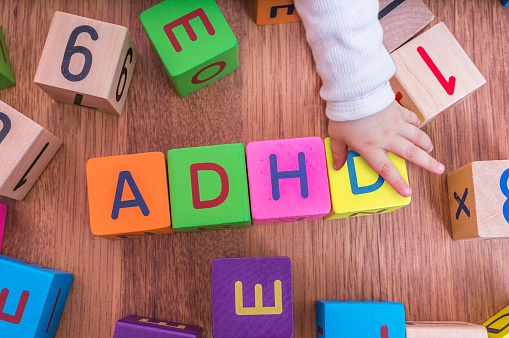 kubus huruf anak-anak, disusun untuk membentuk nama ADHD, dengan tangan anak