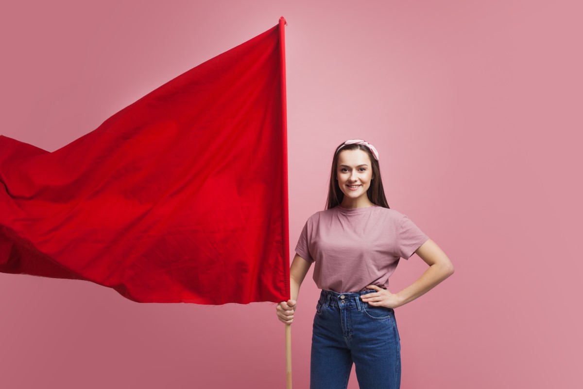 Seorang wanita memegang bendera merah besar sebagai peringatan.