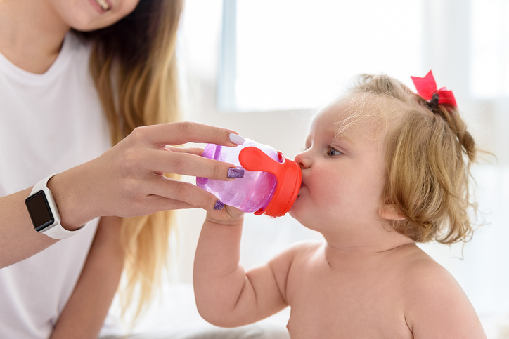 Ibu memberikan air bersih untuk diminum oleh gadis kecil