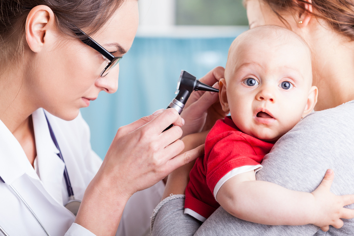 seorang dokter memeriksa telinga anak dengan mesin