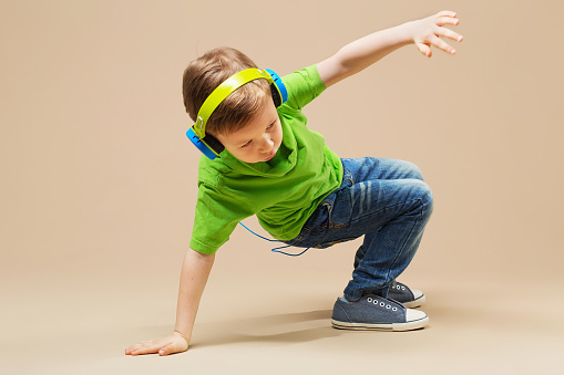 Seorang anak berkemeja hijau dengan headphone sedang melakukan break dance